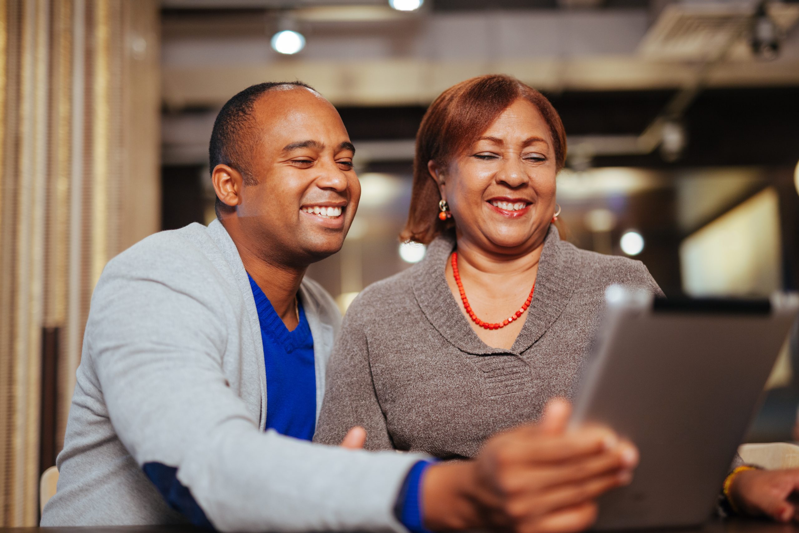 A man and woman laughing at a tablet together